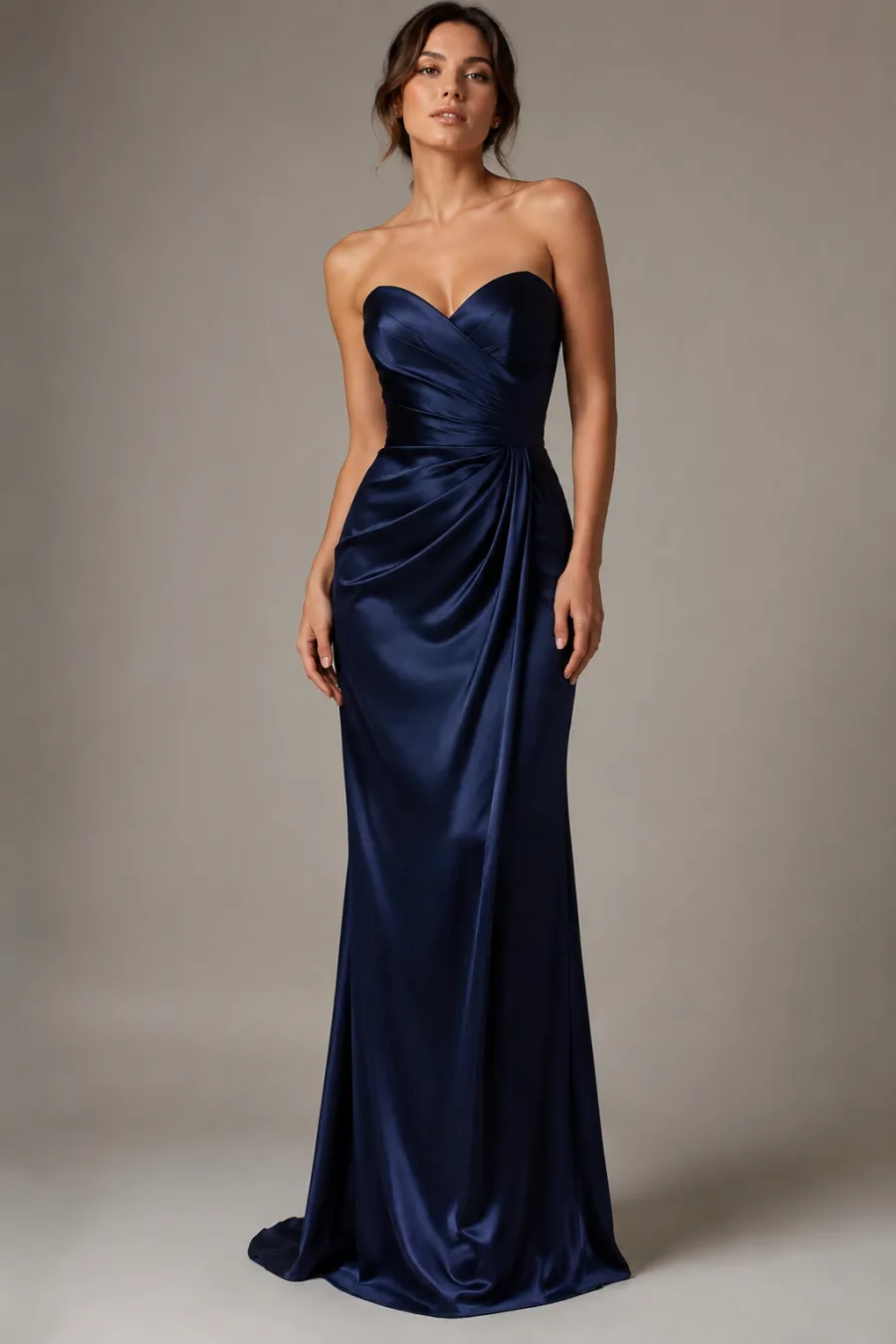 Full-length shot of a floor-length midnight-blue satin evening gown with a sweetheart neckline on a woman, shown on a plain studio background with soft lighting