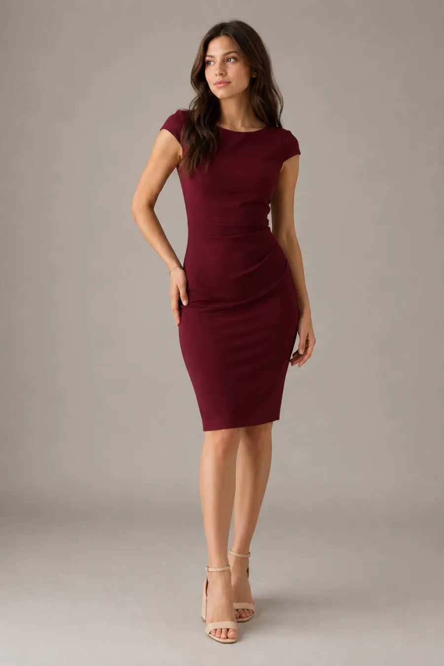 An adult woman trying on a burgundy knee-length sheath dress with cap sleeves and tan block heels for graduation, full body, entire figure from head to feet in frame, centered with headroom