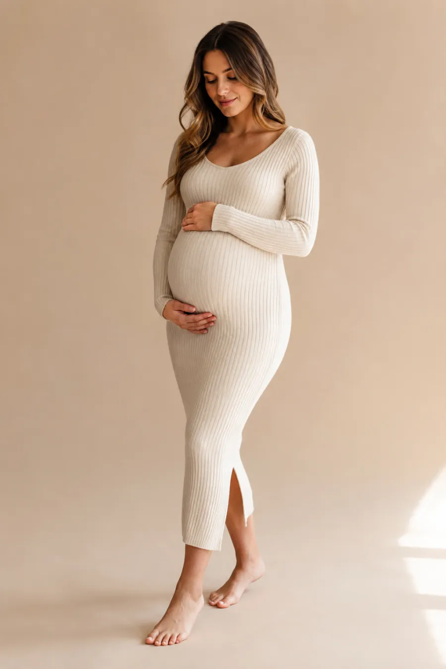 Full-body shot of a cream ribbed-knit fitted maternity dress for a cozy at-home shoot, shown on a plain warm-toned background with soft natural light