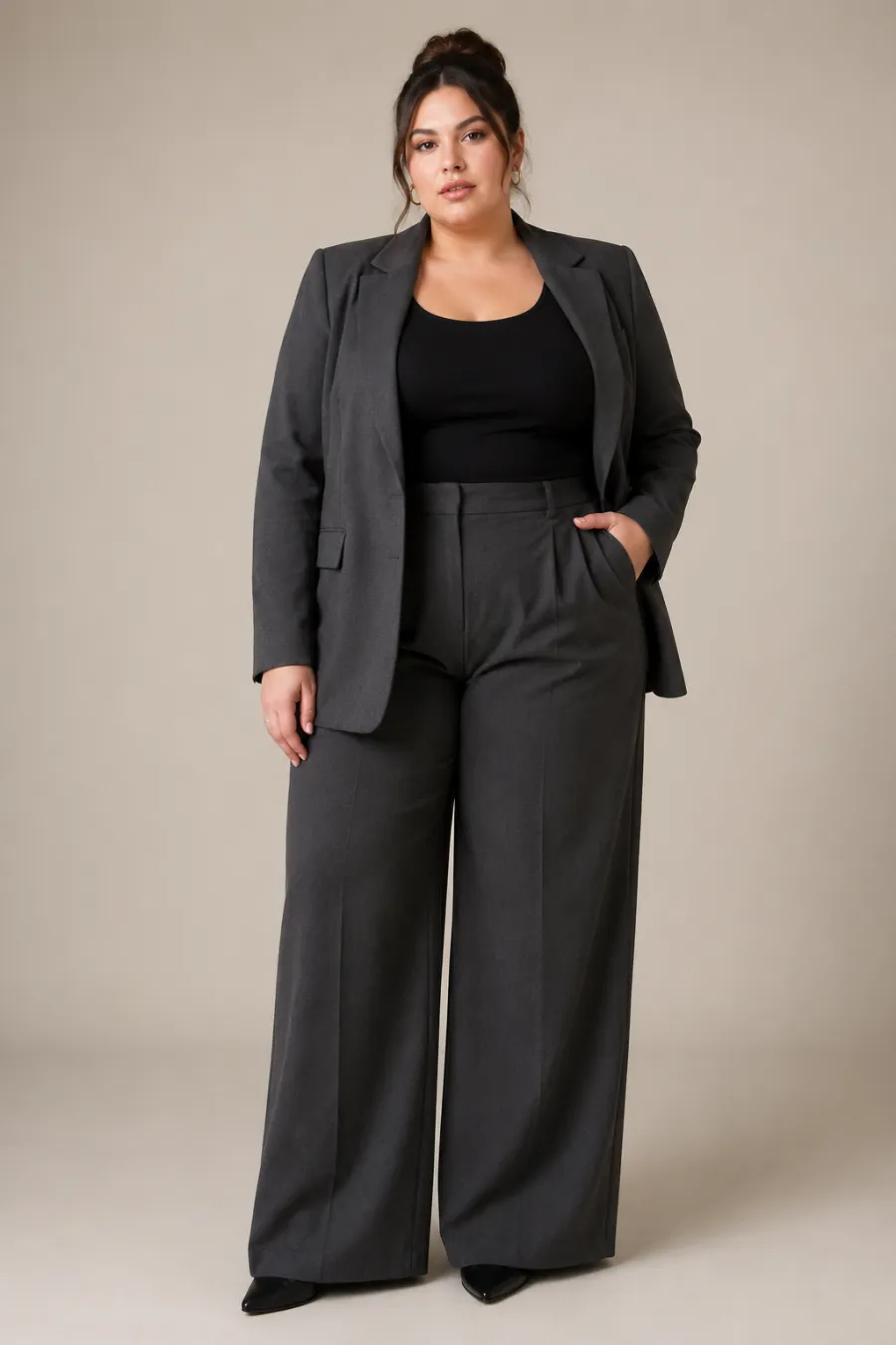 Full-body shot of a plus size business-casual look — a charcoal blazer over a fitted top with wide-leg trousers, on a plain studio background