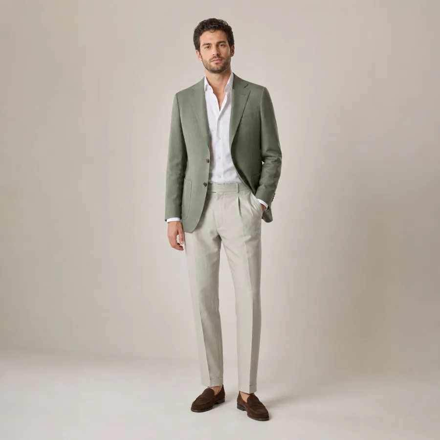 A man in his early thirties wearing a sage-green sport coat over a white open-collar shirt with stone-colored trousers and brown suede loafers, full body, entire figure from head to feet in frame, centered with headroom