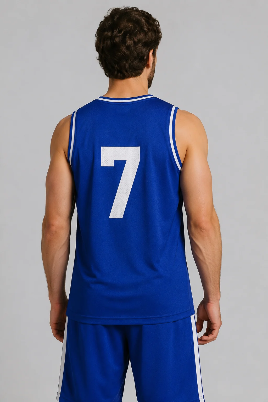 Back view of a person wearing a blue basketball jersey with a custom surname arched above a large white number, plain studio backdrop, even lighting