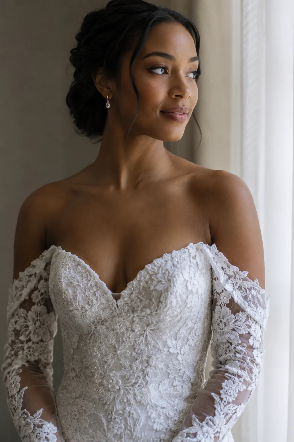 Close framing of a woman in an off-the-shoulder lace bridal gown with a sweetheart neckline, natural window light, soft neutral background